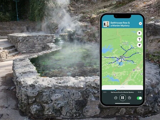 Un bassin de source chaude fumant avec une bordure en pierre à côté d'un chemin pavé.