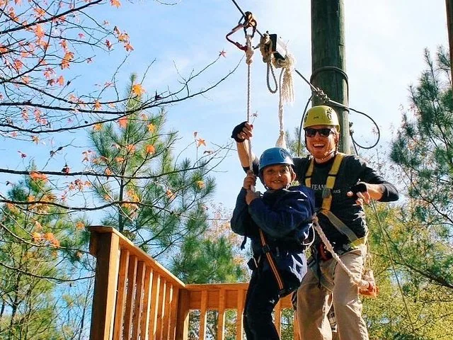 Ein Kind und ein Erwachsener mit Helmen bereiten sich auf das Ziplining vor.